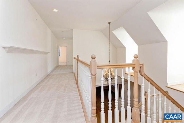 corridor featuring light carpet, a chandelier, and vaulted ceiling