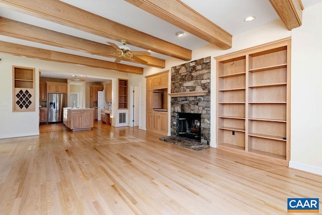 unfurnished living room featuring beam ceiling, ceiling fan, light hardwood / wood-style flooring, built in features, and a fireplace