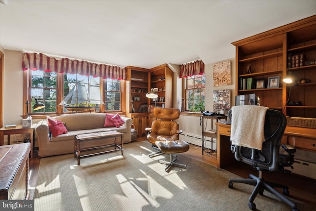 home office with built in features, wood-type flooring, and a baseboard heating unit