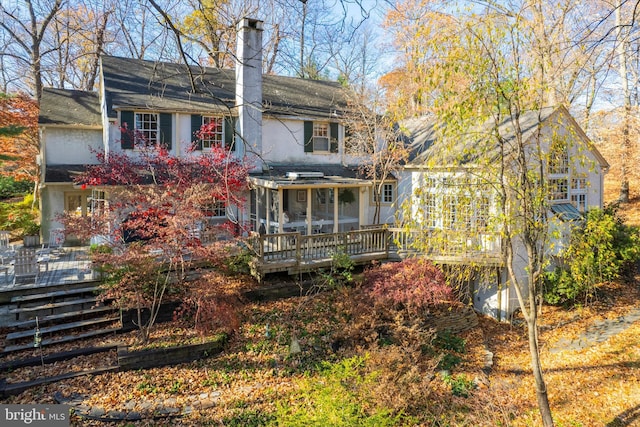 rear view of property featuring a wooden deck and a sunroom