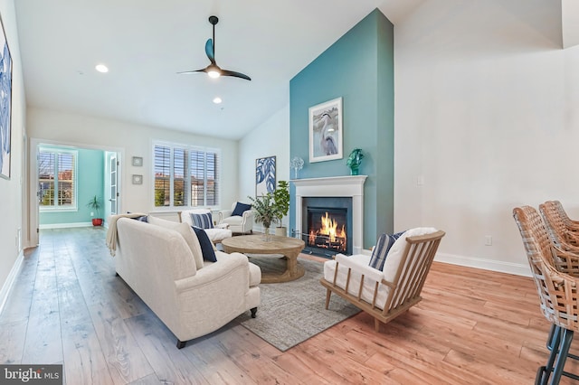 living room with ceiling fan, high vaulted ceiling, and light hardwood / wood-style flooring