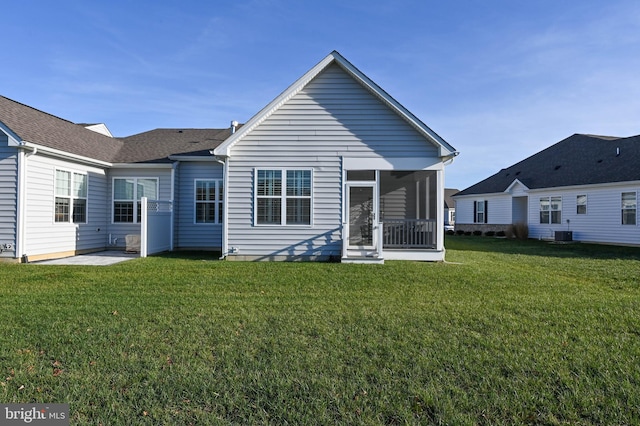 back of property featuring a sunroom, central AC unit, and a yard