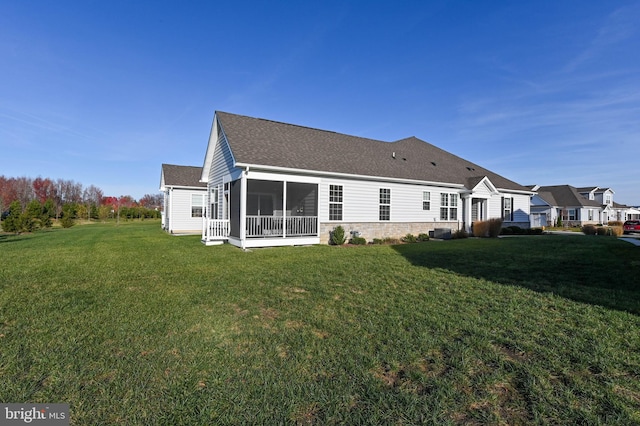 rear view of house featuring a sunroom and a yard