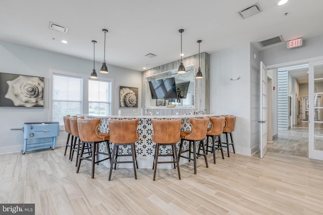 kitchen featuring decorative light fixtures, light wood-type flooring, kitchen peninsula, and a breakfast bar area