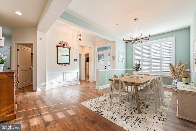 dining area featuring hardwood / wood-style floors, crown molding, and a chandelier