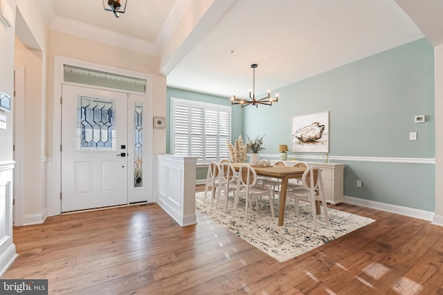 entryway featuring light hardwood / wood-style flooring, crown molding, and a notable chandelier