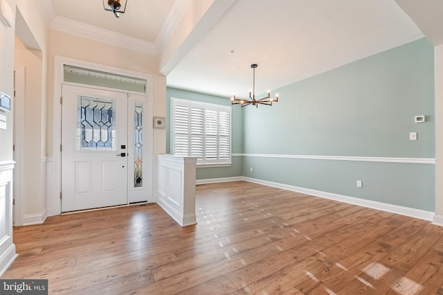 foyer entrance with a chandelier, light hardwood / wood-style floors, and ornamental molding