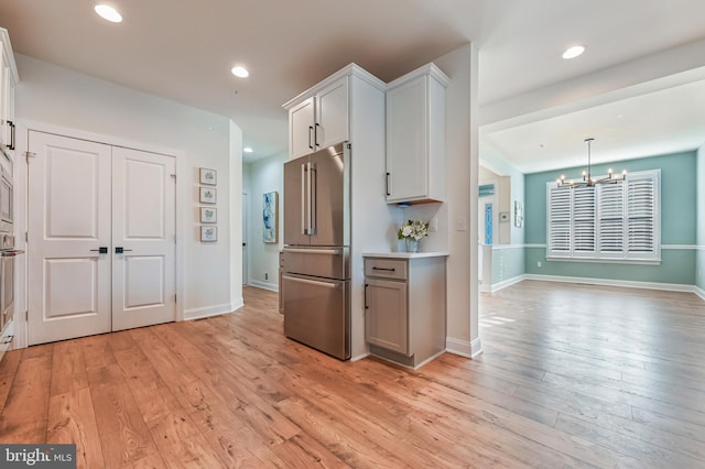 kitchen featuring an inviting chandelier, white cabinets, light hardwood / wood-style flooring, appliances with stainless steel finishes, and decorative light fixtures