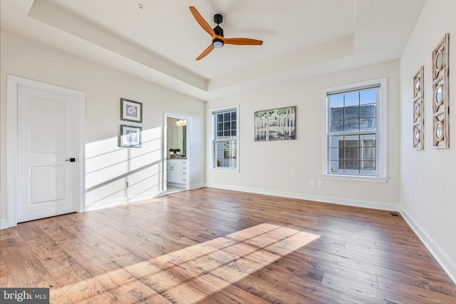 unfurnished room featuring light hardwood / wood-style flooring, a raised ceiling, and ceiling fan