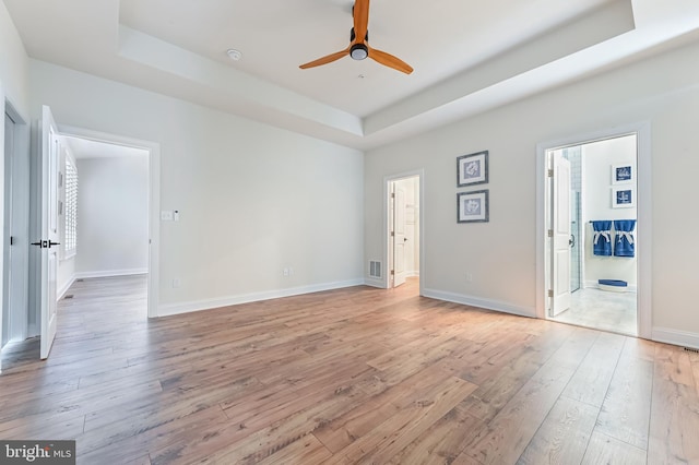 unfurnished room featuring ceiling fan, a tray ceiling, and light hardwood / wood-style flooring