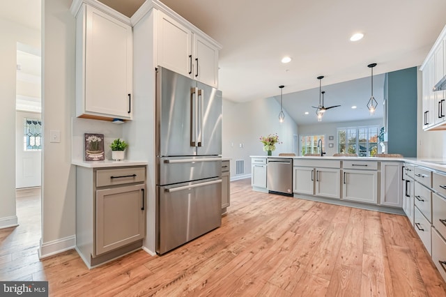 kitchen with ceiling fan, light hardwood / wood-style flooring, stainless steel appliances, and vaulted ceiling