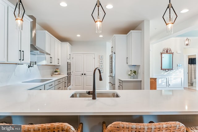 kitchen featuring a breakfast bar, pendant lighting, stainless steel appliances, and wall chimney range hood