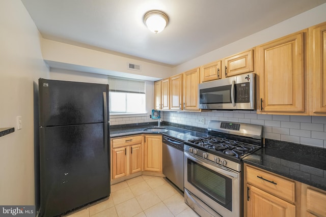 kitchen featuring decorative backsplash, light tile patterned floors, stainless steel appliances, and sink