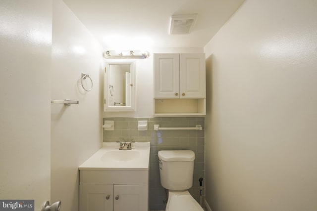 bathroom featuring vanity, toilet, and tile walls