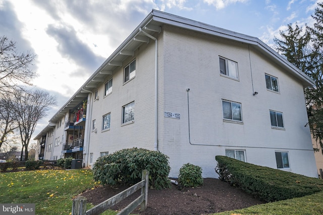 view of property exterior with a lawn and central AC