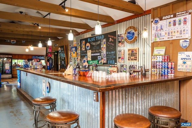 bar with lofted ceiling with beams, decorative light fixtures, concrete floors, and wooden walls