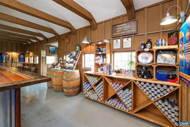 wine room with vaulted ceiling with beams, concrete floors, and wooden walls