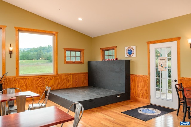 interior space featuring hardwood / wood-style flooring, a healthy amount of sunlight, lofted ceiling, and wooden walls