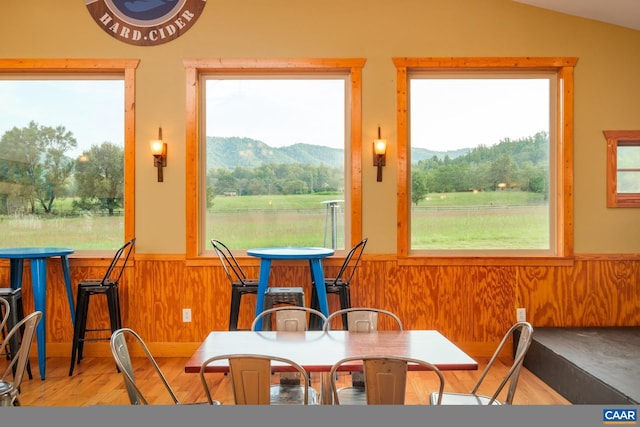 dining room with a mountain view, wood-type flooring, vaulted ceiling, and plenty of natural light