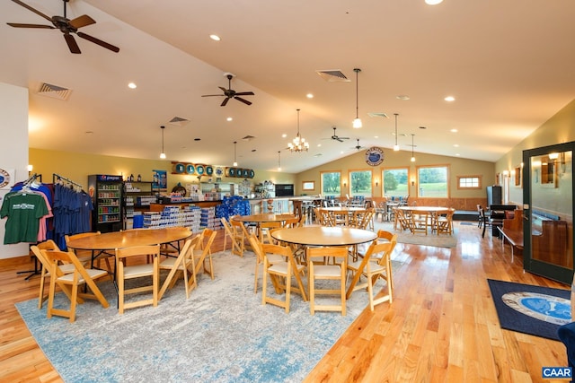 dining area with ceiling fan with notable chandelier, light hardwood / wood-style flooring, and vaulted ceiling