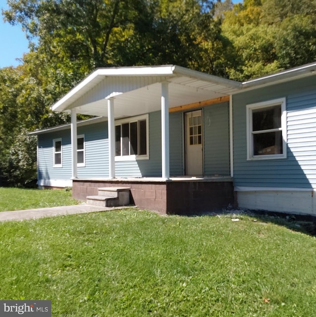 rear view of property with covered porch and a yard