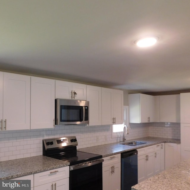 kitchen featuring light stone countertops, tasteful backsplash, stainless steel appliances, sink, and white cabinetry