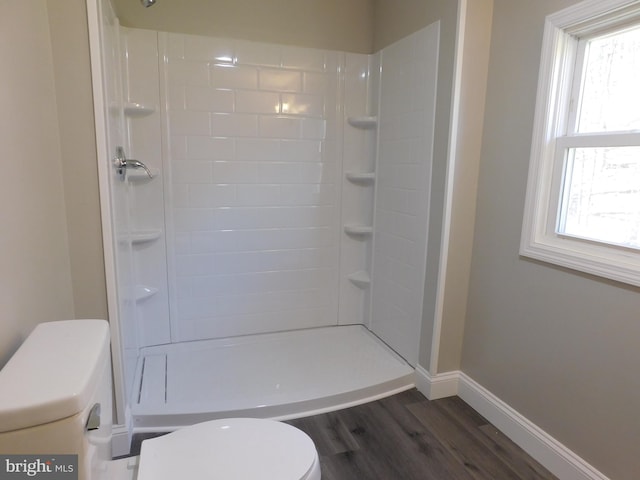 bathroom featuring hardwood / wood-style floors, toilet, and tiled shower