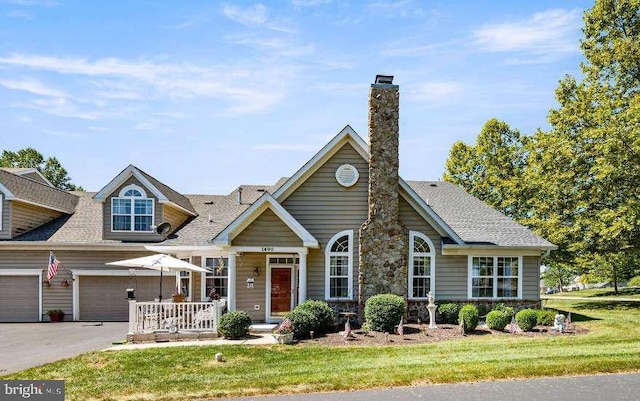 view of front of home with a front lawn, covered porch, and a garage