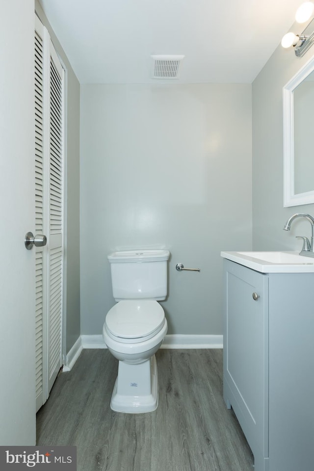 bathroom with hardwood / wood-style floors, vanity, and toilet