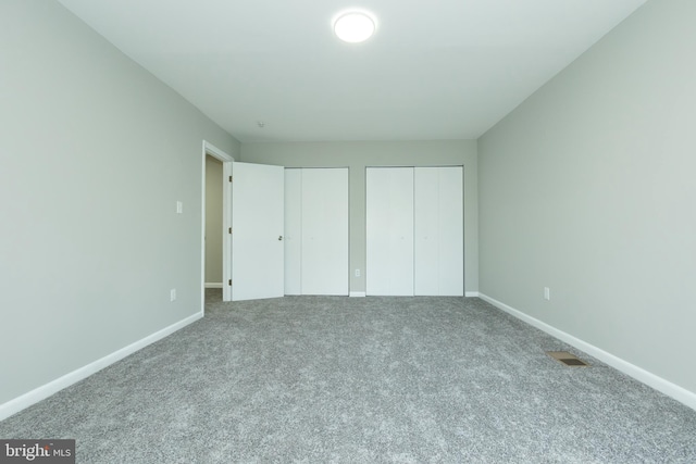 unfurnished bedroom with carpet floors and two closets