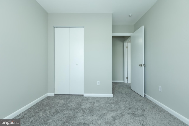 unfurnished bedroom with light colored carpet and a closet