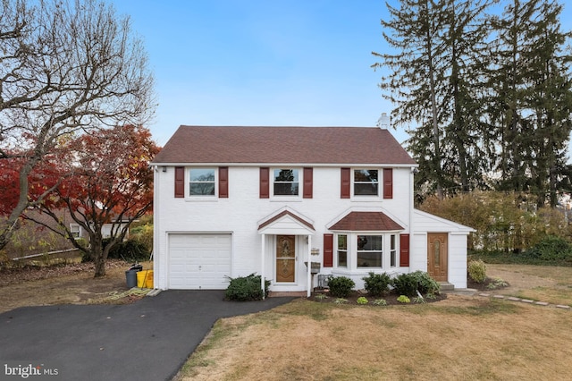 colonial inspired home featuring a front yard and a garage