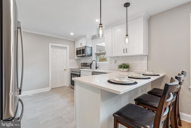 kitchen with pendant lighting, kitchen peninsula, appliances with stainless steel finishes, a kitchen bar, and white cabinetry