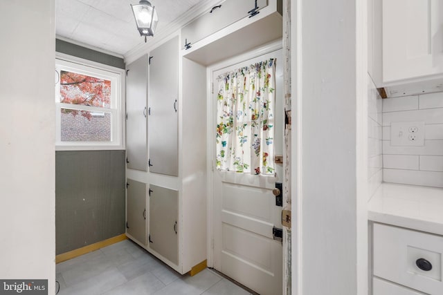 entryway featuring ornamental molding and light tile patterned floors