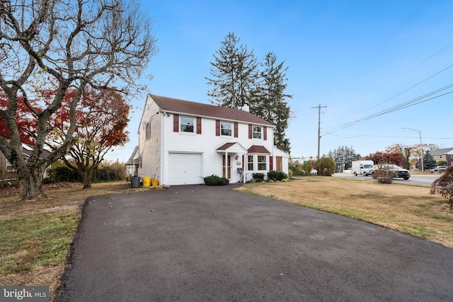 colonial home with a garage and a front lawn