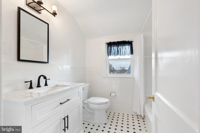 full bathroom featuring vanity, tile patterned floors, vaulted ceiling, toilet, and tile walls