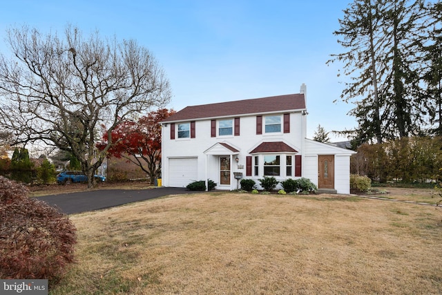 colonial-style house featuring a front yard and a garage