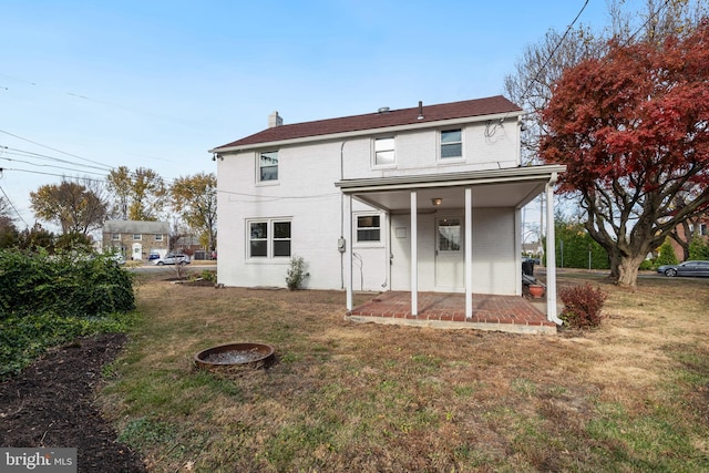 rear view of property featuring a lawn, a porch, and an outdoor fire pit