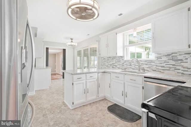 kitchen featuring sink, appliances with stainless steel finishes, kitchen peninsula, white cabinets, and backsplash