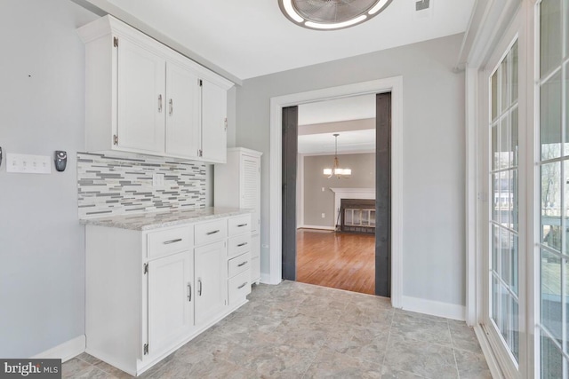 kitchen with tasteful backsplash, a healthy amount of sunlight, and white cabinets