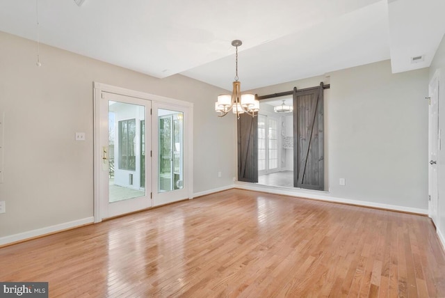 unfurnished dining area featuring a barn door and light hardwood / wood-style floors