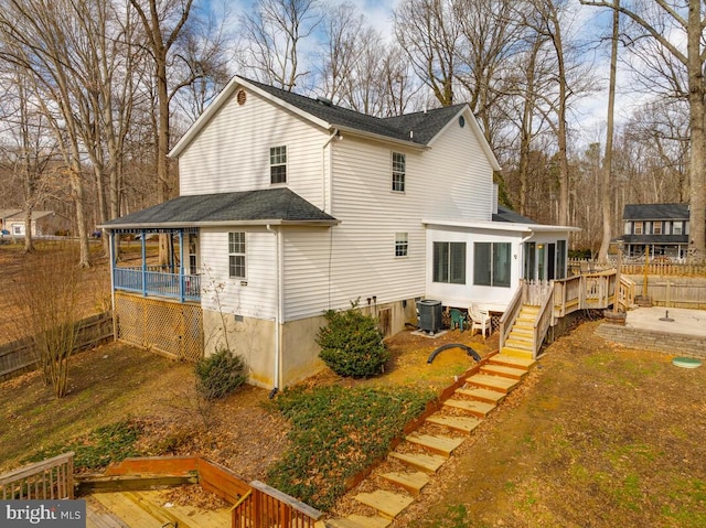 rear view of property featuring a sunroom, a deck, and central air condition unit