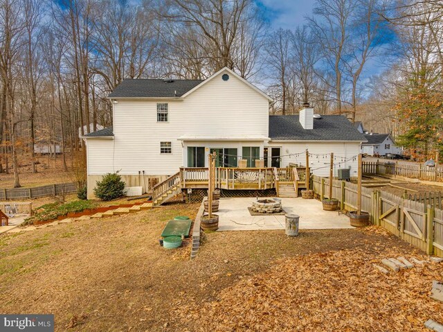 rear view of house with a wooden deck, a fire pit, and a patio