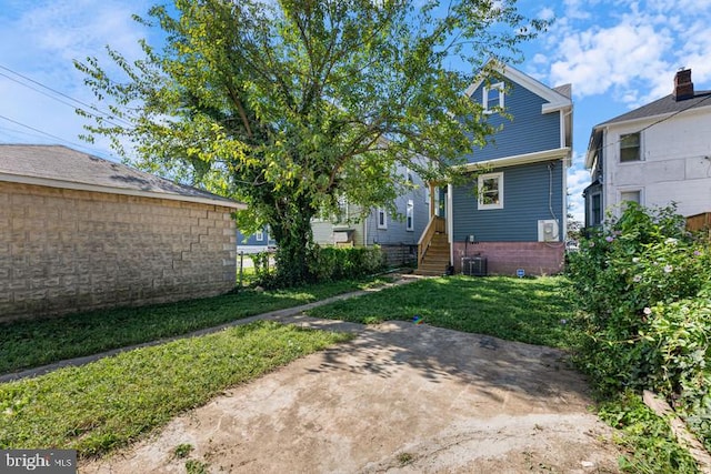 back of property with a yard and central AC unit