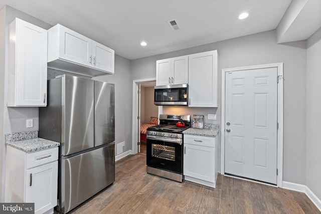 kitchen featuring white cabinets, dark hardwood / wood-style flooring, light stone countertops, and appliances with stainless steel finishes