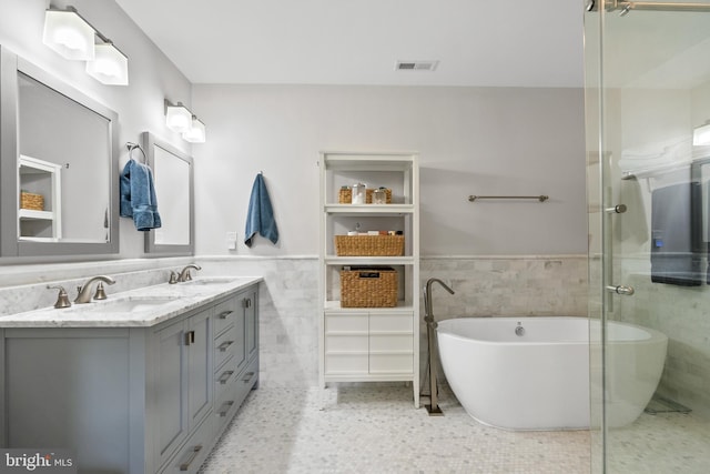 bathroom featuring tile walls, vanity, and a bath