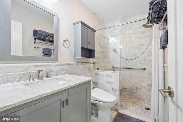 bathroom featuring tile walls, tiled shower, vanity, and toilet