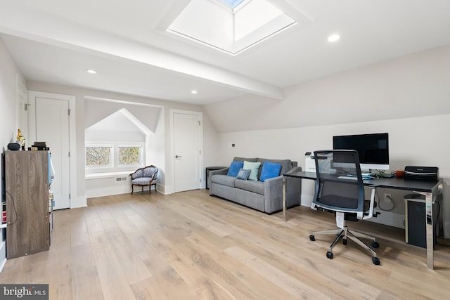 office space featuring light hardwood / wood-style flooring and vaulted ceiling with skylight