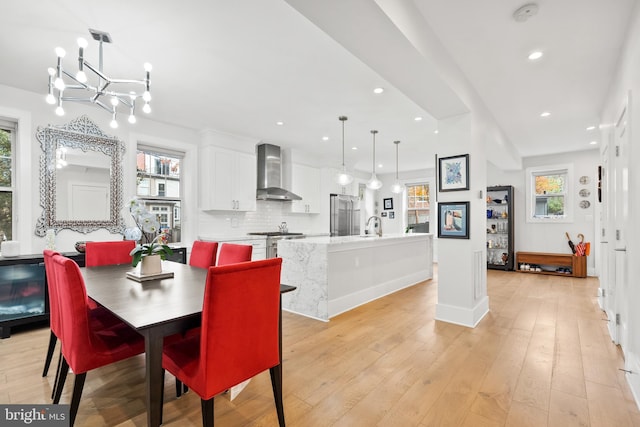 dining area featuring sink, light hardwood / wood-style flooring, and a chandelier