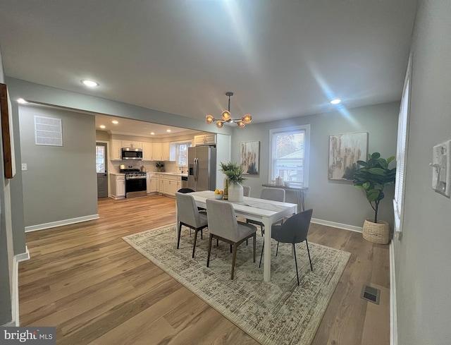 dining space with a chandelier and light hardwood / wood-style floors